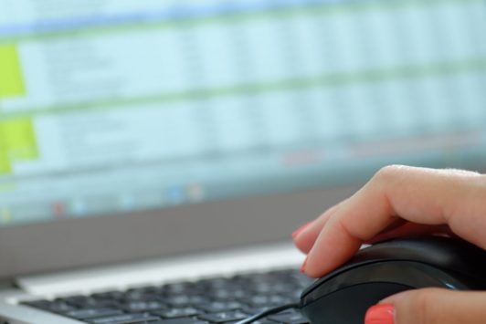 woman's hand with orange nail polish holding black computer mouse