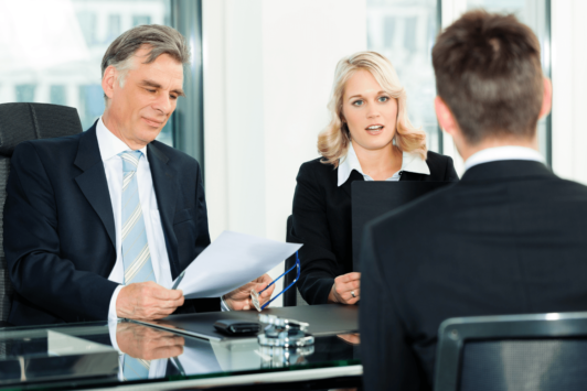 a man and woman in business attire engaged in a job interview skills training session at a table