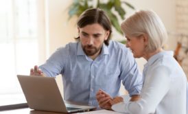 man in blue shirt mentoring an older woman with grey hair