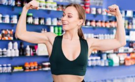 woman wearing black sports bra flexing her arm muscles