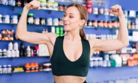 woman wearing black sports bra flexing her arm muscles