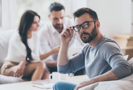 man in grey sweater adjusting glasses with black frame
