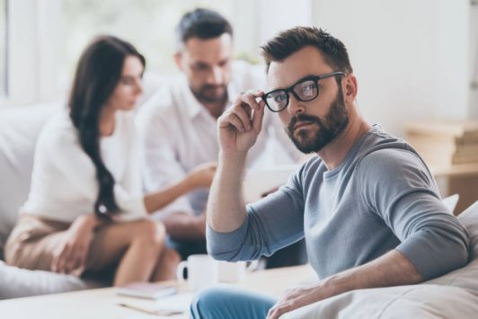 man in grey sweater adjusting glasses with black frame