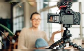 woman wearing light brown sweater recording herself with a camera