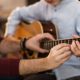 man teaching newbie how to play the guitar