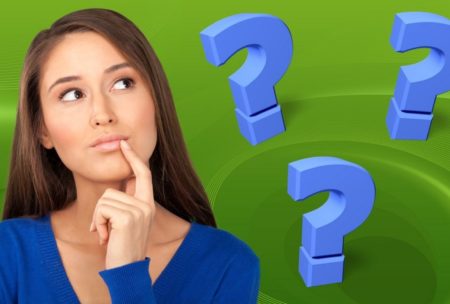 a woman thoughtfully gazes at question marks, hand on chin, reflecting on her decision making skills