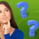 a woman thoughtfully gazes at question marks, hand on chin, reflecting on her decision making skills