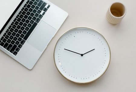 clock cup and silver laptop