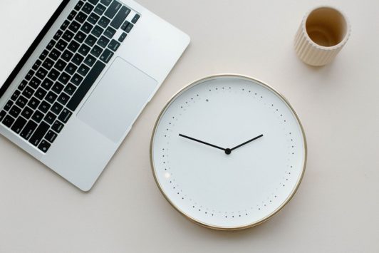 clock cup and silver laptop