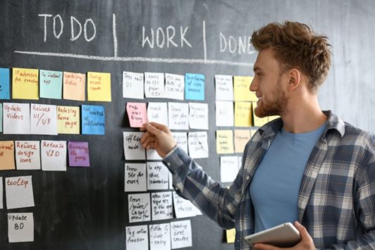 a man, performing his scrum master job, writes a to-do list on a blackboard, organizing tasks for his team