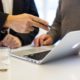 business consultant talking to client pointing at silver laptop