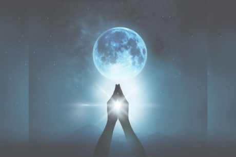 woman raising prayer hands to the moon