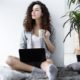 female freelancer holding a cup of coffee and working on laptop