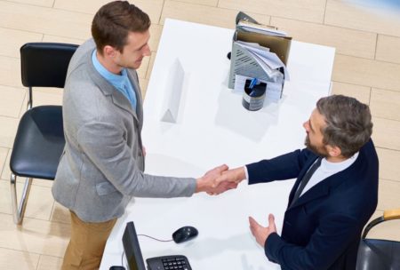 two men at a desk shaking hands, illustrating the culmination of efforts and the essence of closing mastery