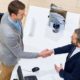 two men at a desk shaking hands, illustrating the culmination of efforts and the essence of closing mastery