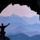 a man stands in a cave with arms outstretched, symbolizing exploration and discovery in a parapsychology course