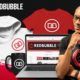 a laptop displaying Redbubble course, surrounded by various clothing items like t-shirts and hoodies
