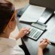 a woman diligently calculates figures on a calculator at her desk, focused on her bookkeeping practice set