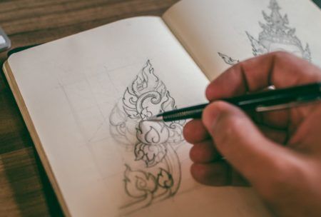 an individual is engaged in basic drawing on a notebook with a pen, illustrating their artistic process and concentration