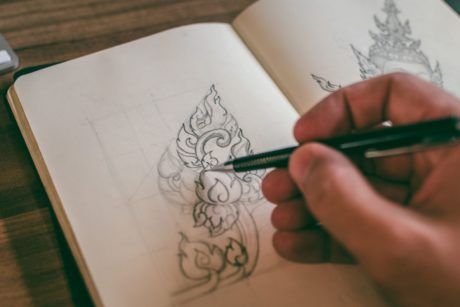 an individual is engaged in basic drawing on a notebook with a pen, illustrating their artistic process and concentration