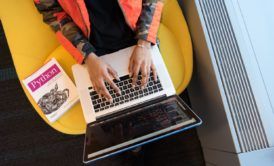 a person sitting on a yellow chair with a laptop, studying the best course in python