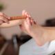 A woman receiving a foot massage using a wooden stick during a reflexology course