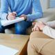 a man and woman engaged in discussion on a couch, using a pen and paper during acceptance and commitment therapy training