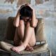 a woman, curled in a worn chair, her head in her hands, overcoming cptsd