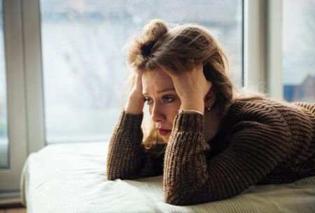 a woman with her head in her hands thinking how to stop worrying