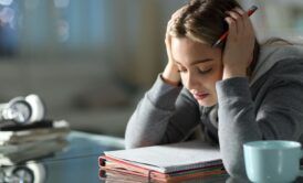 A woman, visibly frustrated, sits at a desk with her head in her hands, seeking effective memorization techniques