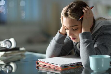 A woman, visibly frustrated, sits at a desk with her head in her hands, seeking effective memorization techniques