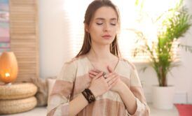 Woman practicing energy psychology techniques, meditating with her hands on her chest.