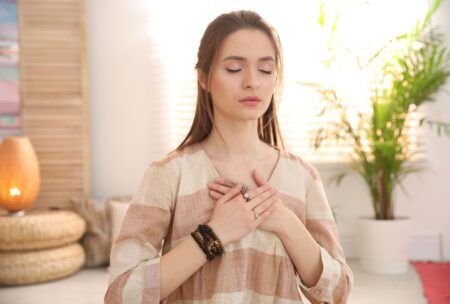 Woman practicing energy psychology techniques, meditating with her hands on her chest.