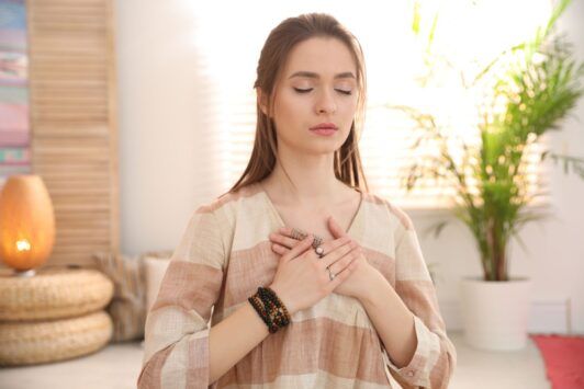 Woman practicing energy psychology techniques, meditating with her hands on her chest.