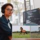 A woman wearing headphones focuses on a computer screen displaying a zebra. This image relates to a deep learning course.