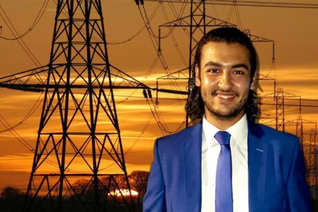 A man in a suit and tie stands before electricity pylons, conducting fault analysis.