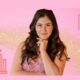 A woman in a pink dress stands confidently against a shimmering gold background, symbolizing Growth Mindset Mastery