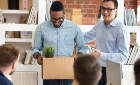 Two men holding a box with a plant, symbolizing the importance of mastering employee onboarding.