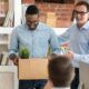 Two men holding a box with a plant, symbolizing the importance of mastering employee onboarding.