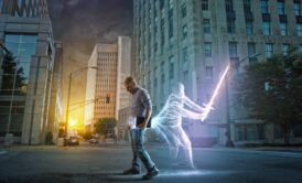 A man strolls through the street with a spirit holding a light saber as part of the spirit guide course