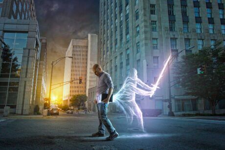 A man strolls through the street with a spirit holding a light saber as part of the spirit guide course