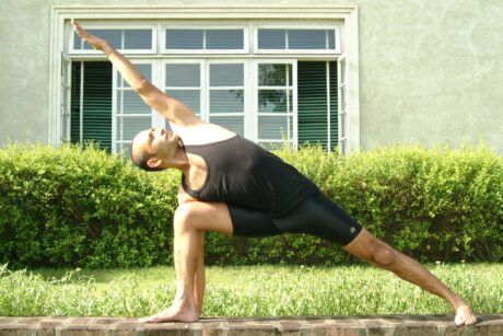 A man practicing a yoga pose outdoors, promoting yoga for busy people seeking relaxation and balance.