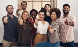 People from different backgrounds showing thumbs up, symbolizing relentless optimism.