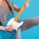 A person in a striped shirt and jeans playing an electric guitar, skillfully mastering guitar chords