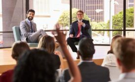 two business professionals seated, one gesturing with hand, discussing becoming a thought leader