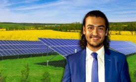 A man in a suit and tie standing in front of solar panels, showcasing solar energy design