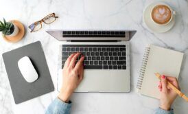 a woman's hands on a laptop keyboard on a marble table, discovering how to use google workspace