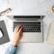 a woman's hands on a laptop keyboard on a marble table, discovering how to use google workspace