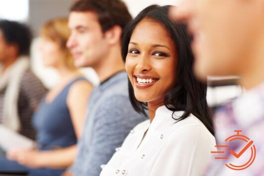 A woman smiling in front of a group of people, showing teamwork and unity.