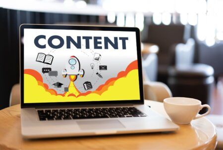 visual representation of content creation for websites, showing a laptop with a cup of coffee nearby